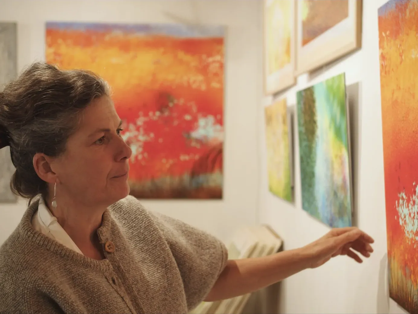 Anne Turlais hanging her paintings on the white walls of Galerie Artwave